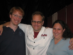 A photograph of Alton Brown with his arms around Eric and Kat.