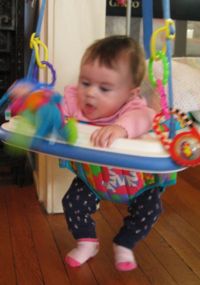 Carolyn happily jumps about in her 'bouncy seat', a chair suspended from a door frame and incorporating a spring so that she can bounce up and down even though she hasn't the coordination to stand yet.