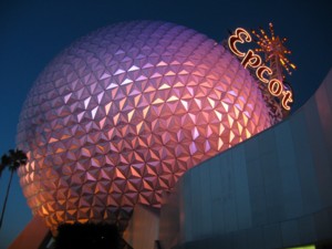 A photograph of the Spaceship Earth globe, illuminated by purple and pink lights in the deep twilight of a Florida evening.