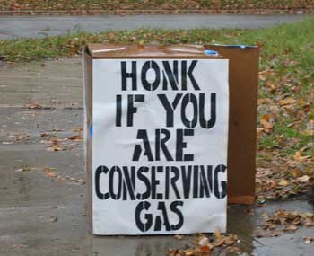 A home-made sign reading, in big blocky stencil lettering, 'Honk if you are conserving gas'.