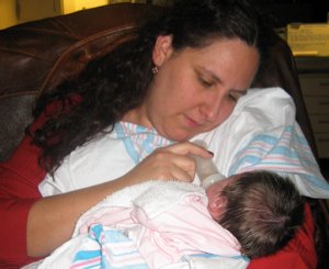 Kat sits in a chair and feeds our new daughter for the first time.